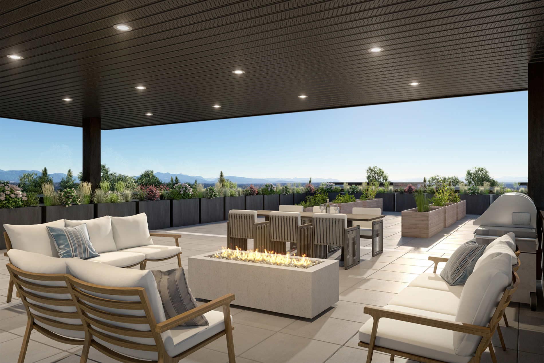 Outdoor rooftop terrace at Amson Bloc Surrey featuring lounge seating, fire pit, dining area, and landscaped planters with mountain views, located at 5937 144 Street in Panorama Ridge Surrey
