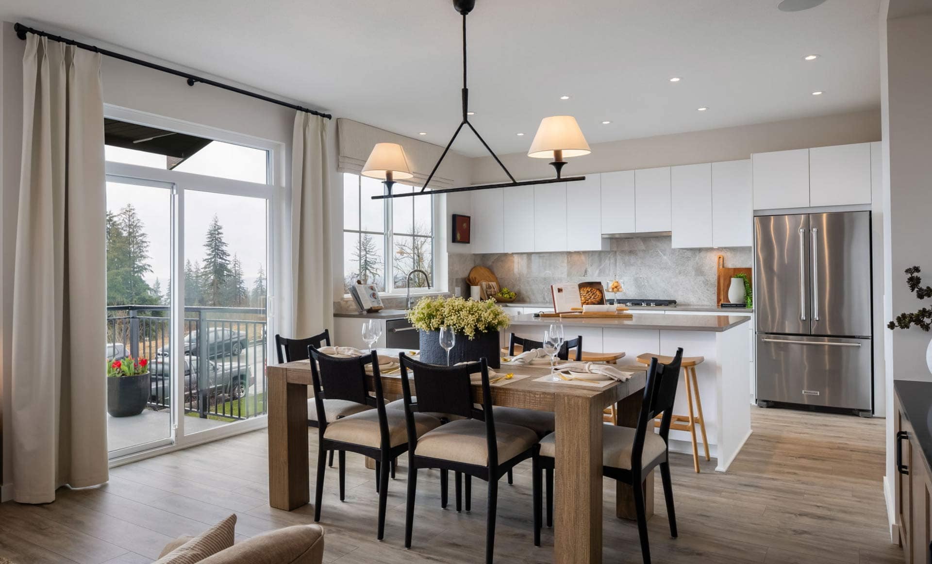 Dining and kitchen area at Ridgewood Burke Mountain townhomes featuring large windows, modern kitchen, and access to outdoor space at 3637 Sheffield Avenue Coquitlam