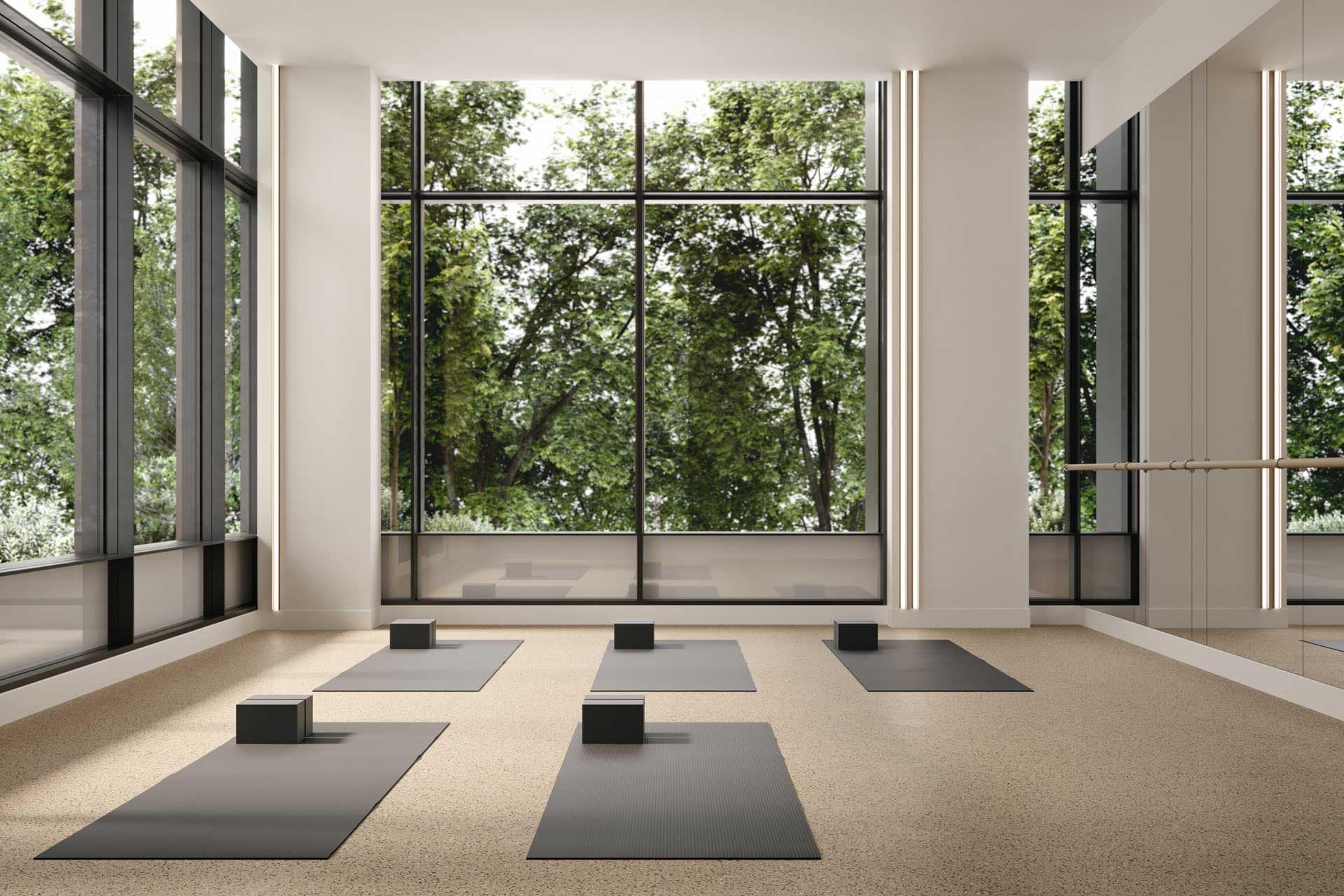 Yoga studio at Jinju Coquitlam condos by Anthem Properties, located at 533 Cottonwood Avenue in Burquitlam, featuring yoga mats, mirrored wall, and large windows with greenery views.