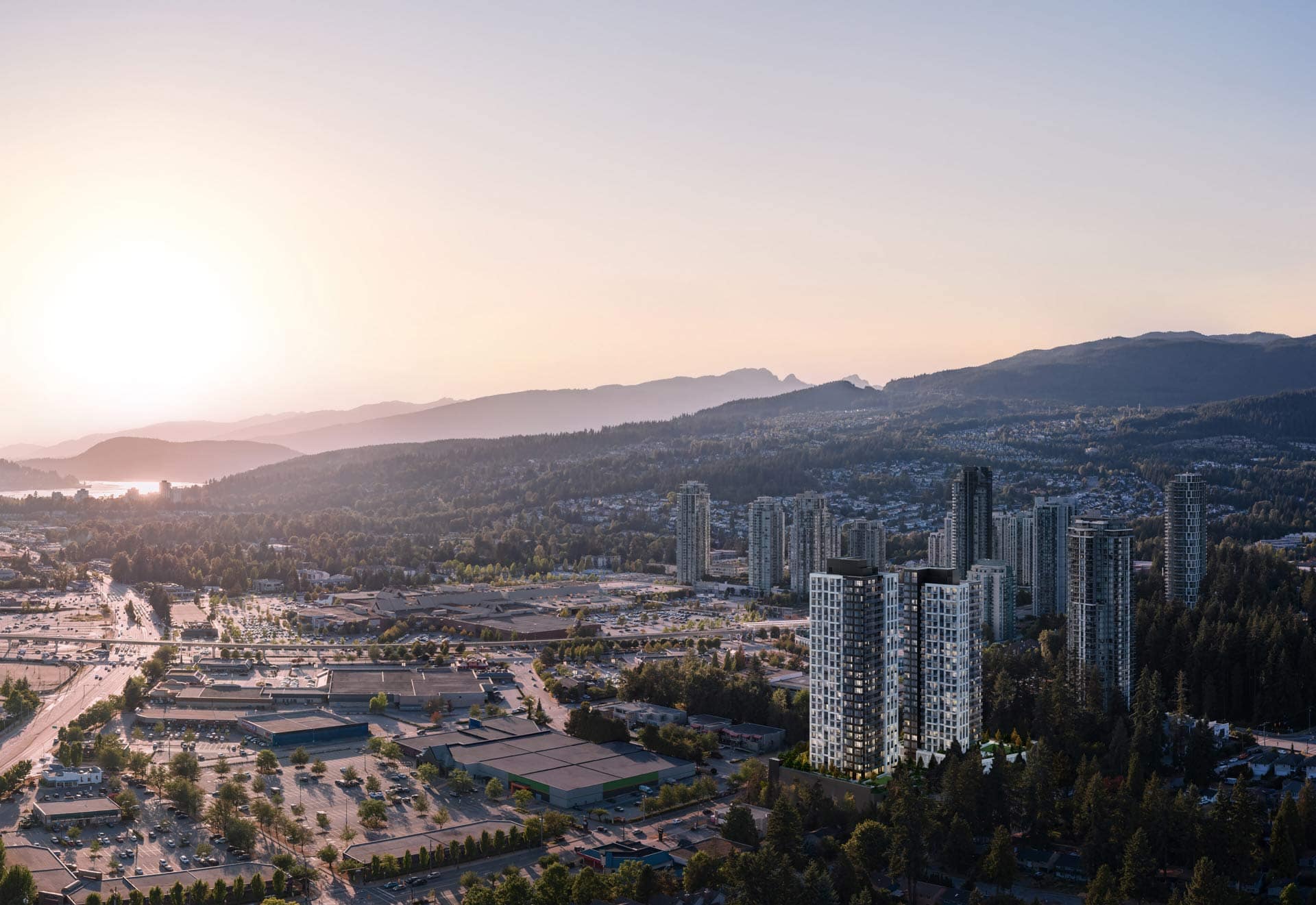 Aerial view of Coquitlam Town Centre skyline near Town & Centre by Mosaic at 3650 Westwood Street, showing surrounding buildings, shopping areas, and mountain backdrop