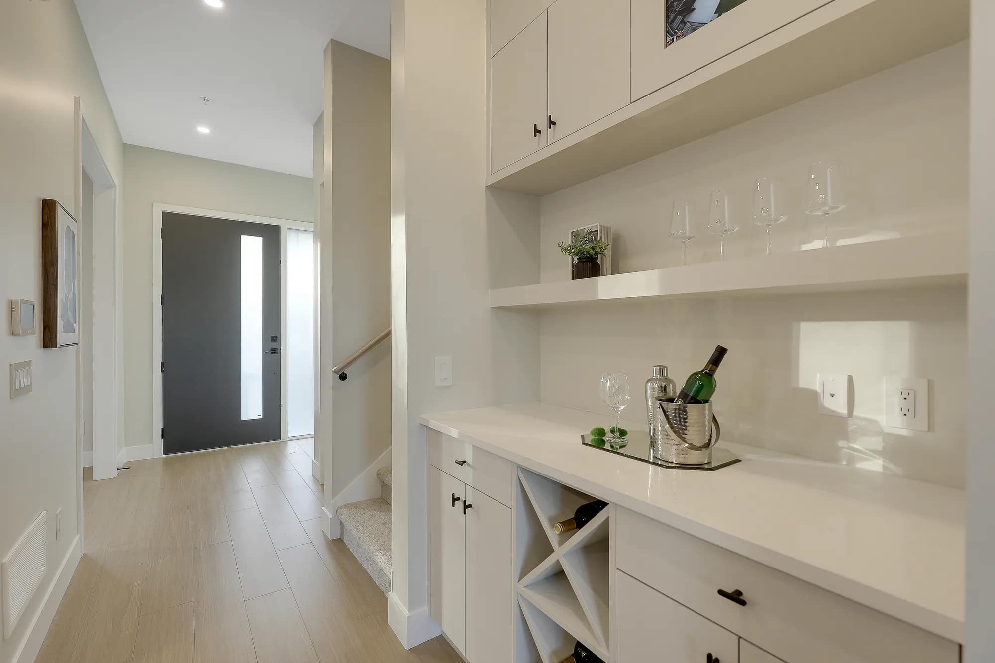 Built-in beverage and storage station at Latimer Landing Langley by Archstone, located at 7760 196 Street. The space features quartz countertops, custom cabinetry, open shelving, integrated wine storage, modern hardware, and convenient access from the home's main living area.
