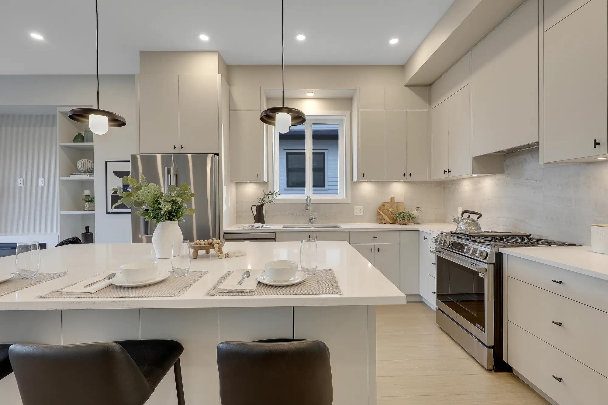 Modern kitchen at Latimer Landing Langley by Archstone featuring a large quartz island, stainless steel appliances, full-height cabinetry, pendant lighting, contemporary fixtures, and open-concept connection to the living area.