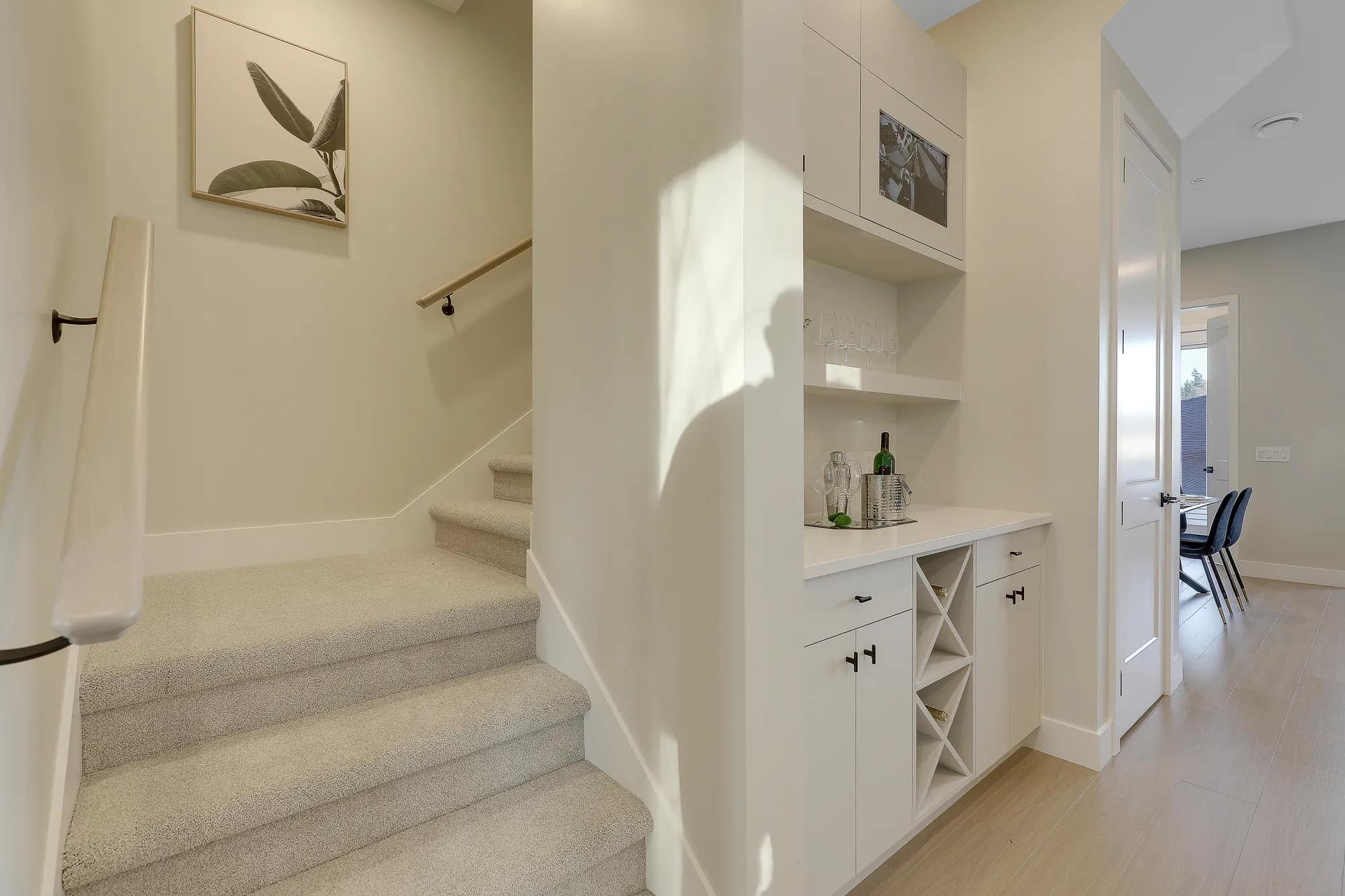 Interior staircase and built-in storage area at Latimer Landing Langley by Archstone featuring custom cabinetry, wine storage, quartz countertops, carpeted stairs, modern finishes, and efficient use of space throughout the home.