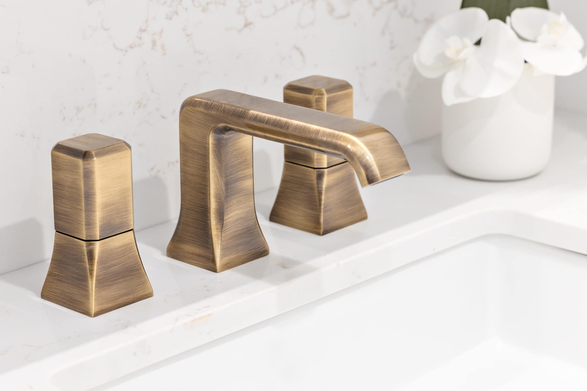 Brushed brass bathroom faucet on white quartz countertop at Italia by Solterra in Vancouverโs Fairview