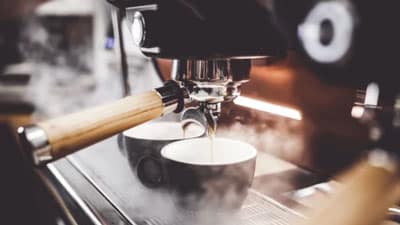Espresso pouring into two cups on a machine, promoting the Friday Morning Coffee real estate newsletter signup