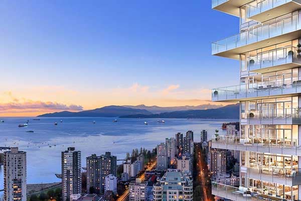 Sunset view from 1535 Howe Vancouver by Onni featuring luxury glass balconies overlooking English Bay, Downtown Vancouver skyline, and North Shore mountain scenery from residences at 1335 Howe Street.