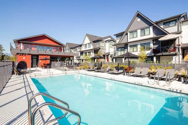 Outdoor pool and clubhouse at Nature's Walk Pitt Meadows by Onni Group featuring lounge seating and modern townhomes at 19451 Sutton Avenue