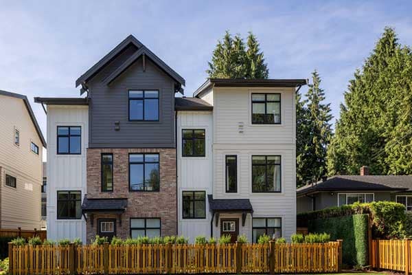 Front elevation of Rindall Port Coquitlam townhomes showing a mix of red brick and modern siding, pitched rooflines, large windows, and private fenced front yards in a Woodbridge Homes development at 2150 Rindall Avenue in Central Port Coquitlam.