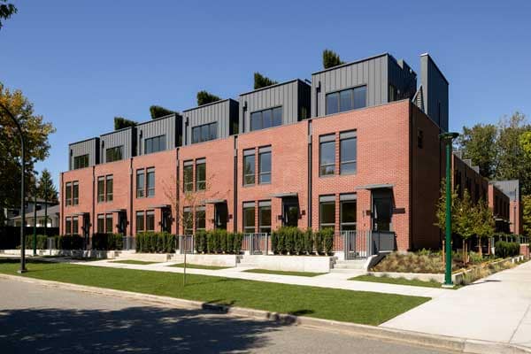Street-level exterior view of York Vancouver, a modern collection of brick townhomes by Listrator at 802 West 37th Avenue in Vancouver’s Cambie Corridor, featuring park-front homes with rooftop levels, landscaped pathways, and contemporary West Side architecture.