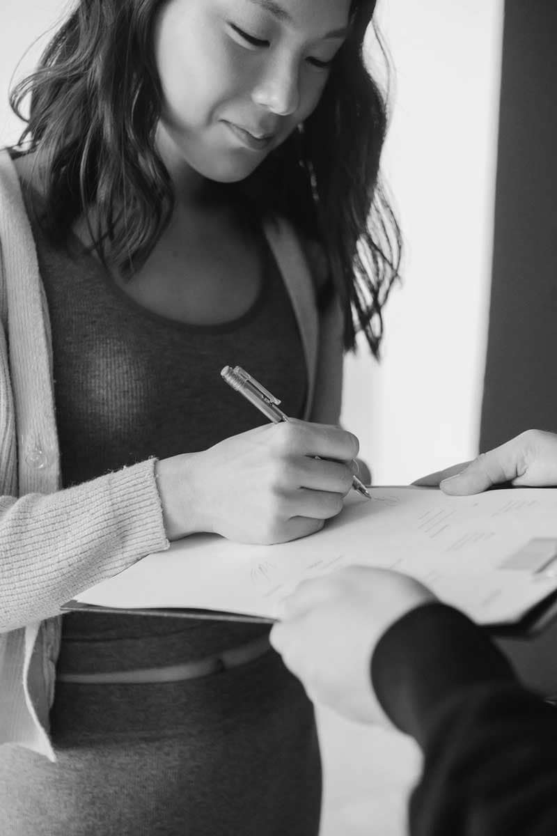 Prospective tenant signing rental paperwork during a consultation with a Metro Vancouver rental advisor, representing a professional Vancouver tenant placement service focused on tenant screening, lease preparation, and residential rental placement.
