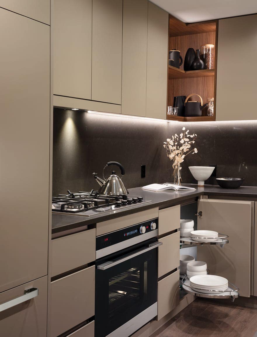 Kitchen storage and appliance detail at Smith & Farrow presale development in Coquitlam West by Boffo Developments, located at 720 Farrow Street, featuring integrated oven, gas cooktop, custom cabinetry, pull-out corner storage, open shelving, and refined contemporary finishes.