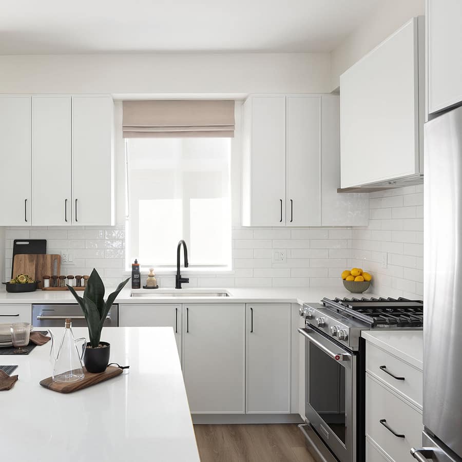 Bright kitchen at Rindall Port Coquitlam with white shaker cabinets, quartz countertops, subway tile backsplash, and gas range in a Woodbridge townhome.