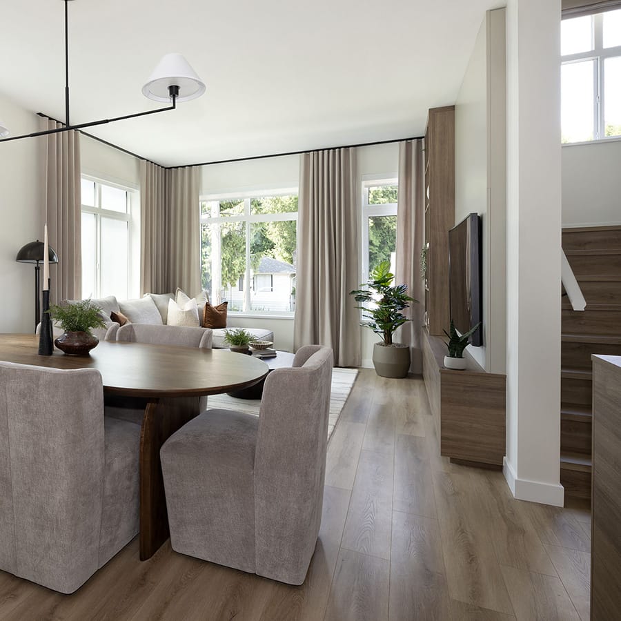 Open-concept living and dining area at Rindall Port Coquitlam featuring wide-plank flooring, large corner windows, custom media cabinetry, and neutral finishes in a modern Woodbridge townhome at 2150 Rindall Avenue in Central Port Coquitlam.