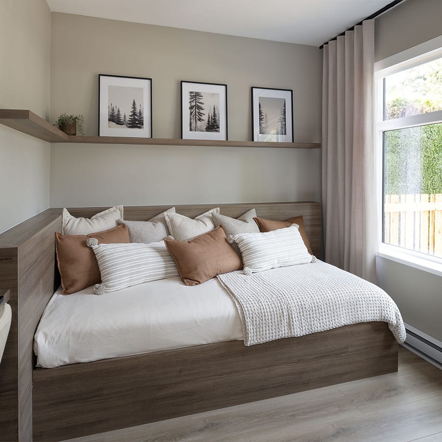 Secondary bedroom at Rindall Port Coquitlam with built-in platform bed, integrated wood shelving, soft neutral tones, and large window in a thoughtfully designed Woodbridge townhome.