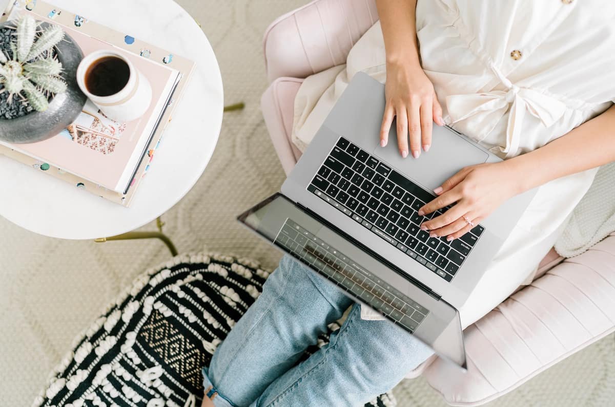 Woman sitting comfortably in an armchair with a laptop, searching Google for MLS listings.